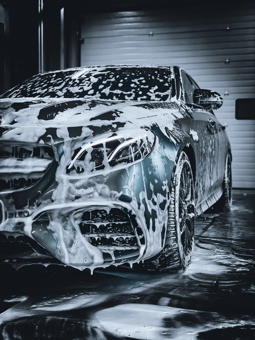 Autolavado a domicilio: Auto de lujo cubierto de espuma durante autolavado premium