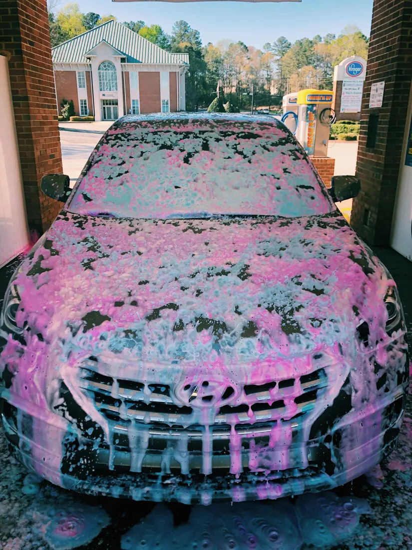 Autolavado premium: Auto cubierto de espuma rosa durante lavado
