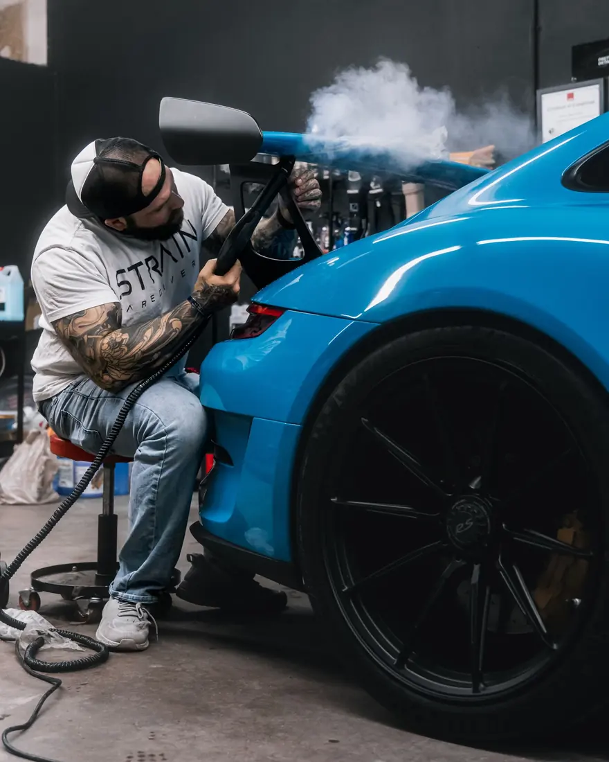Polish para auto: Detallista pule la pintura azul de un deportivo con pulidora